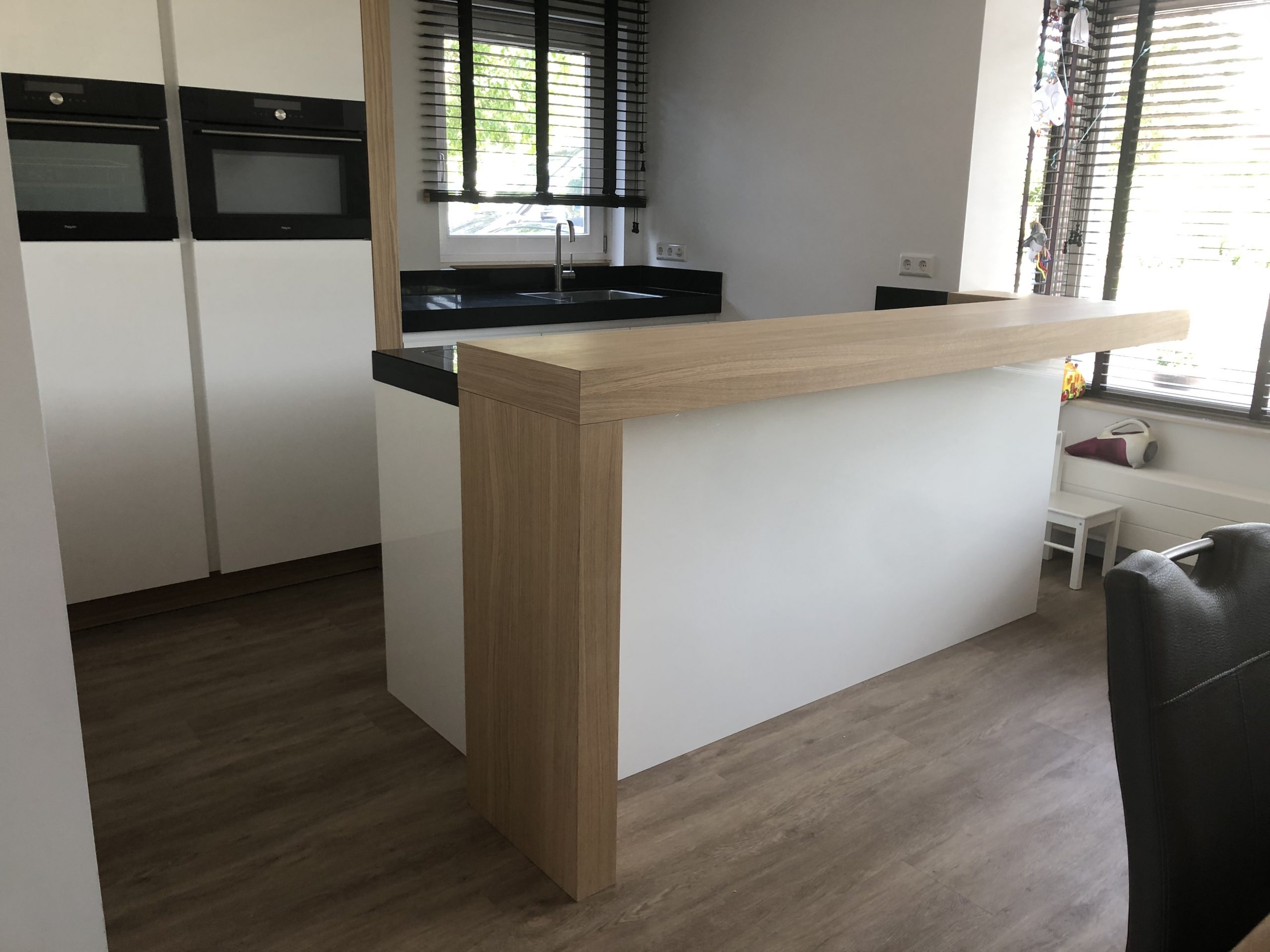 Geplaatste witte keuken met houten barblad en ingebouwde ovens