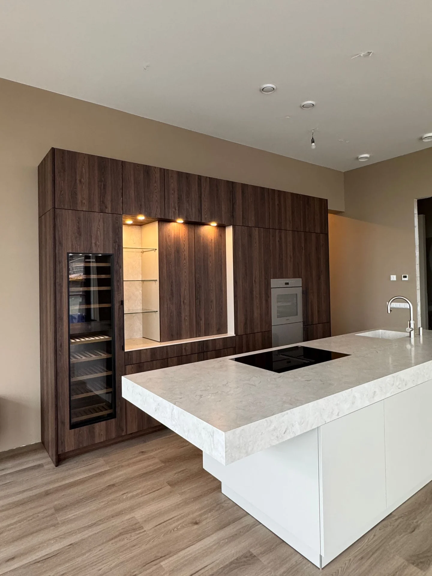 Witte keuken met kookeiland en houten kastenwand